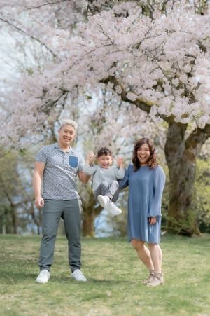 A joyful family moment under blooming pink cherry blossom trees on a spring day.