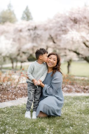 A tender spring moment shared beneath beautiful blooming cherry trees in a serene garden setting.