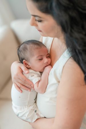 Intimate motherhood moment as parent gently nurses newborn baby in soft, natural lighting.