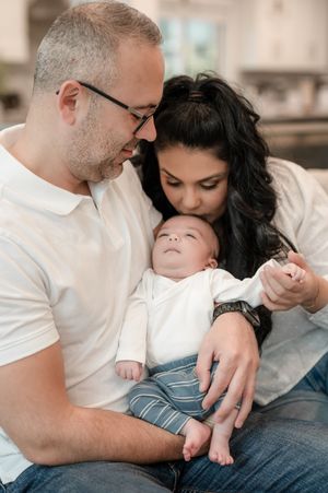 Parents sharing an intimate bonding moment with their newborn baby while relaxing on a couch.