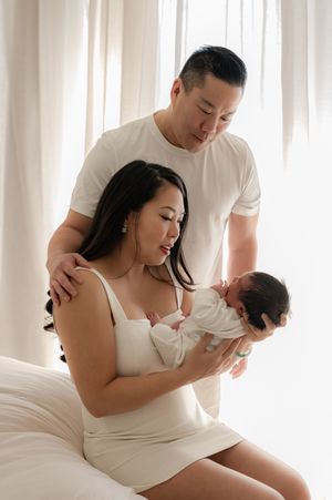 Expecting parents share tender moments in a bright white bedroom during maternity photoshoot sequence.
