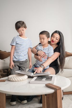 A family sits together on a couch looking at a photo album while sharing a tender moment at home.