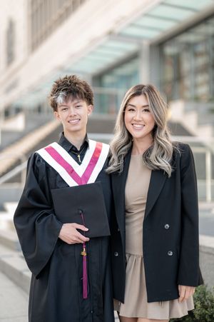 Graduates in black academic regalia and a guest pose together during a graduation photo session.