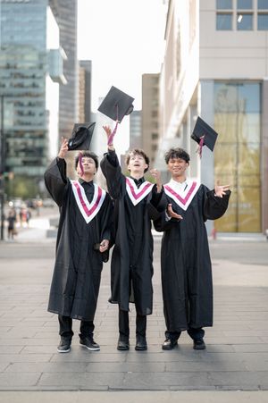 A group of graduates celebrate by throwing their graduation caps in the air on campus.
