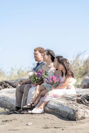 Four connected moments show a group sitting together on driftwood at a beach, sharing laughter and holding flowers.