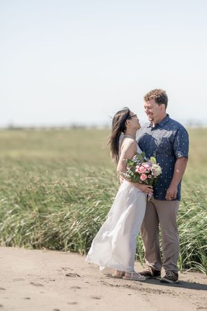 A couple shares a romantic moment in a field of tall grass during their engagement photo session.