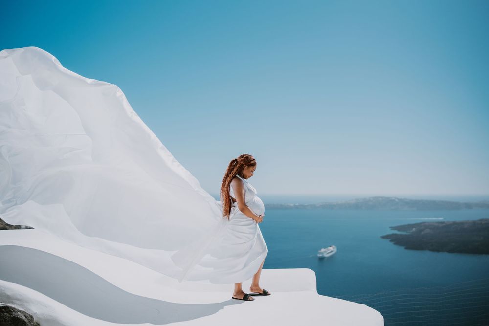 Elegant bridal portrait on white Santorini architecture with sea views.