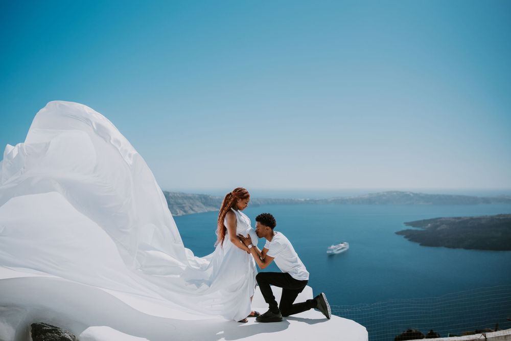 Romantic proposal moment on white Santorini rooftop overlooking the Aegean Sea.