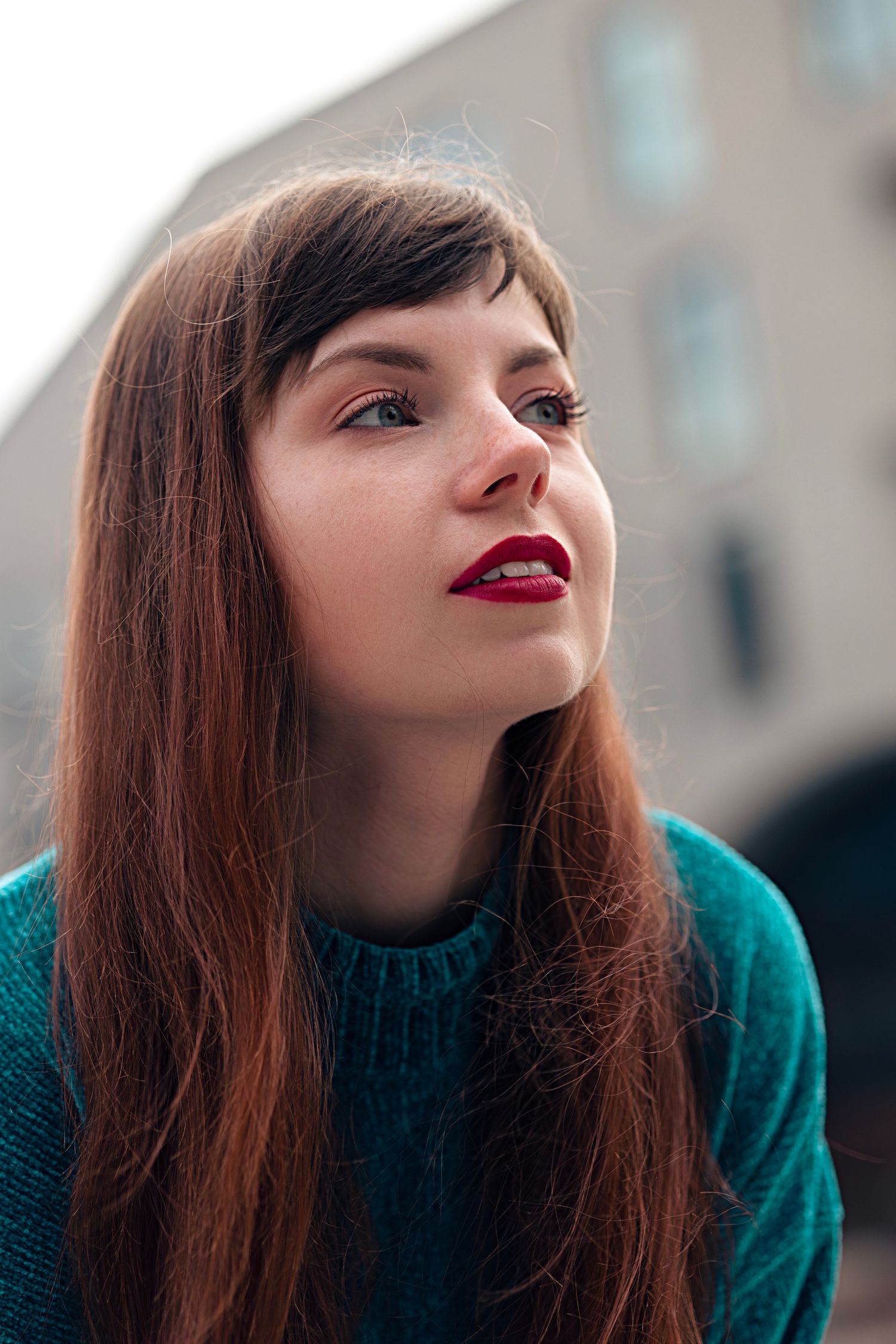 The red-haired girl looks into the distance with hope in her eyes.  Сlose-up portrait.
