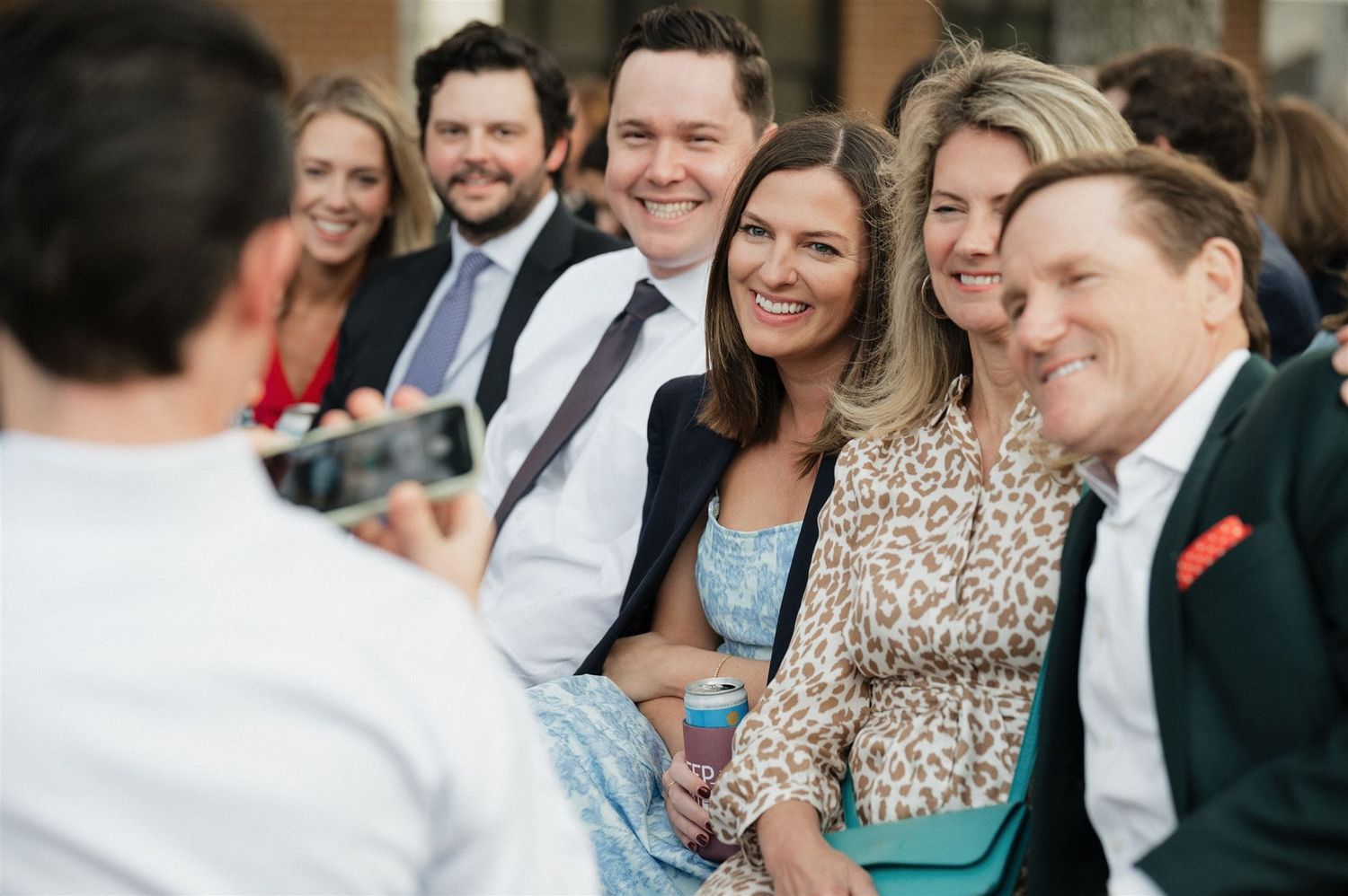 Wedding guests seated outdoors smiling during a celebration.