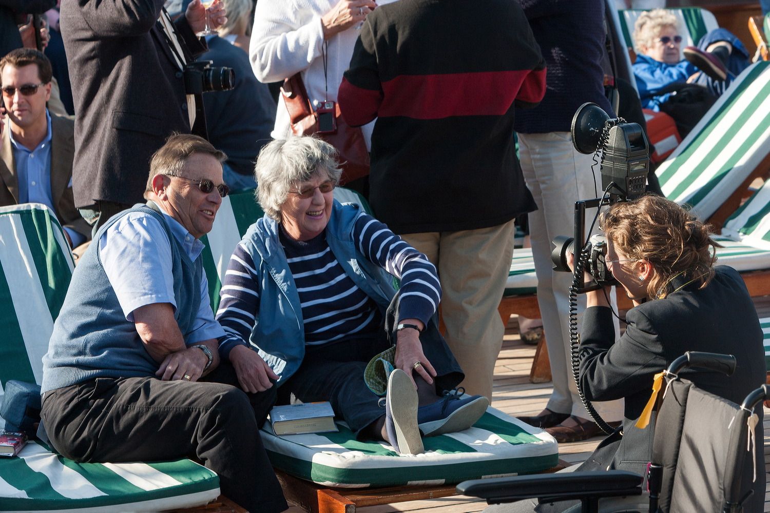 Passengers relaxing in deck chairs aboard a cruise ship during daytime.