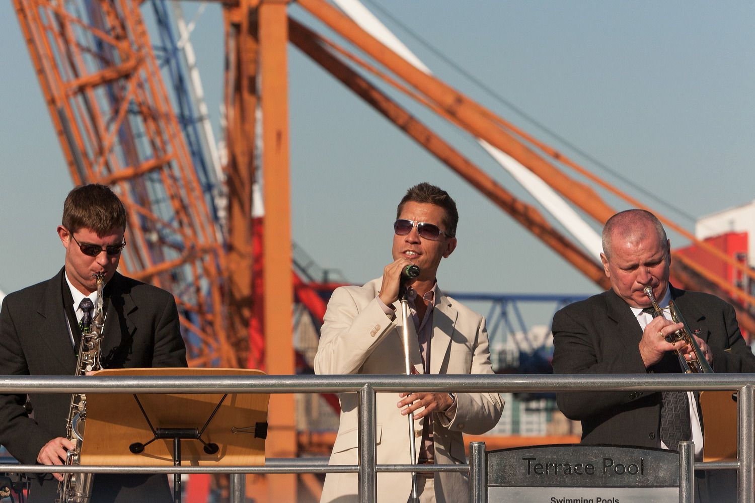 Maritime officials conducting business on ship deck with orange crane visible in background.