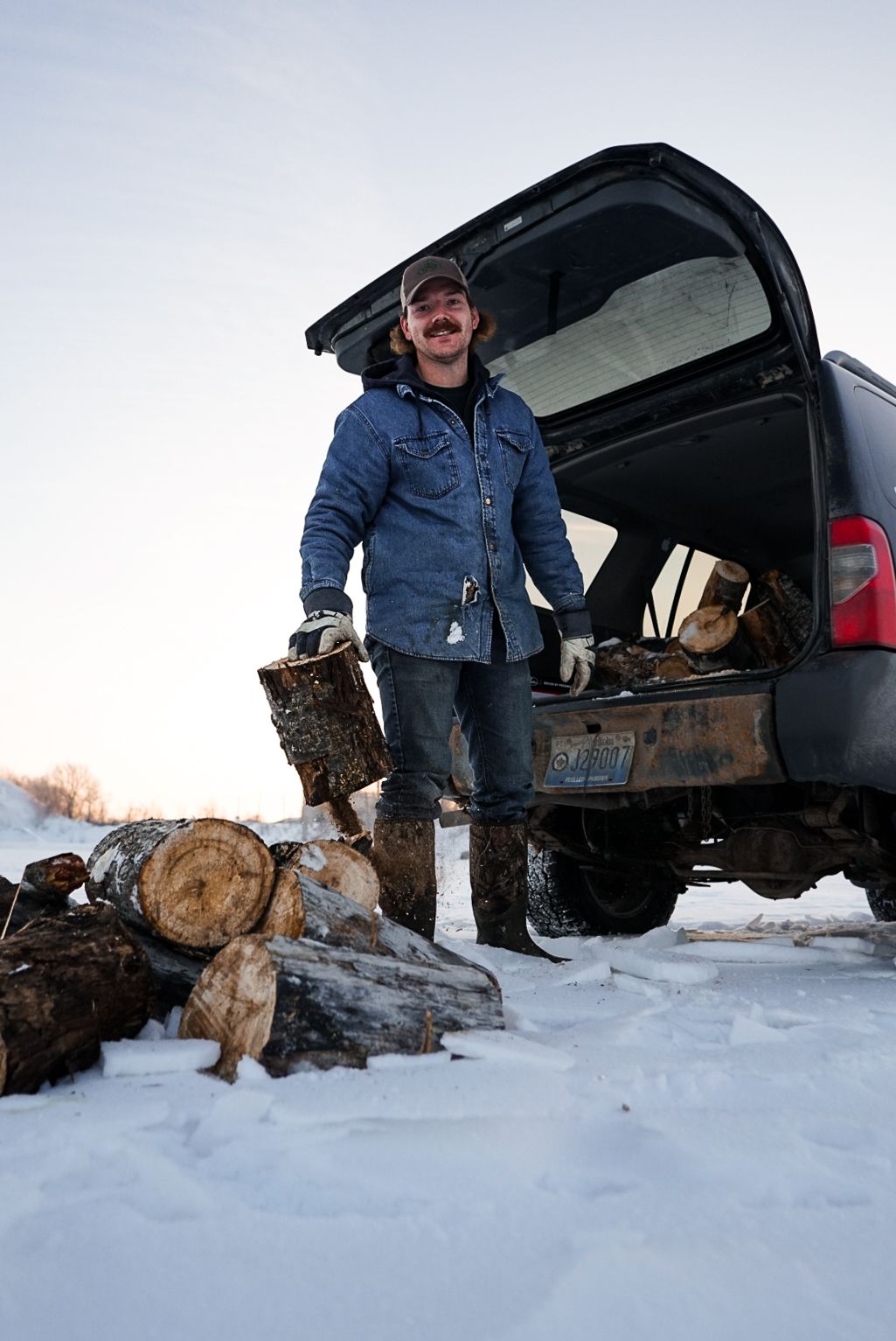 A pickup truck parked in snowy conditions with hunting gear and dogs visible in the back.