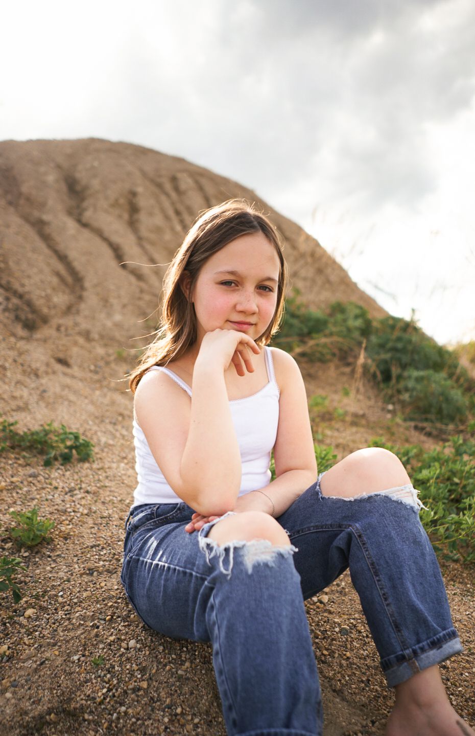 A casual portrait on a sandy hill with natural lighting and earthy tones.