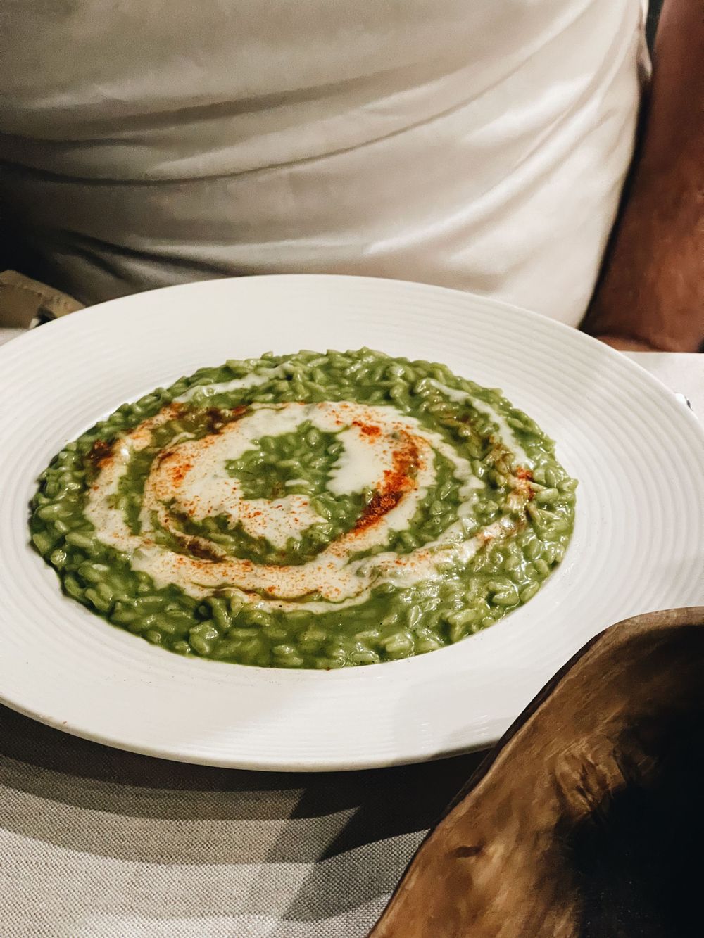 Creamy green risotto dish presented with a decorative swirl on a white plate.