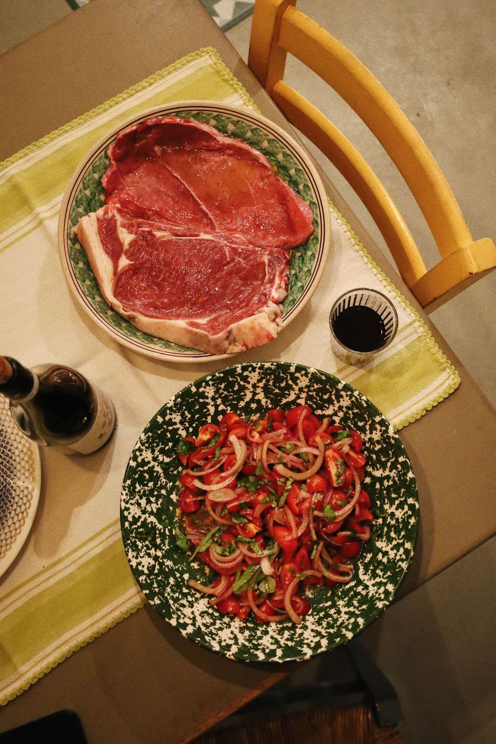 Fresh raw steaks and sliced red peppers arranged on a decorative plate for dinner preparation.