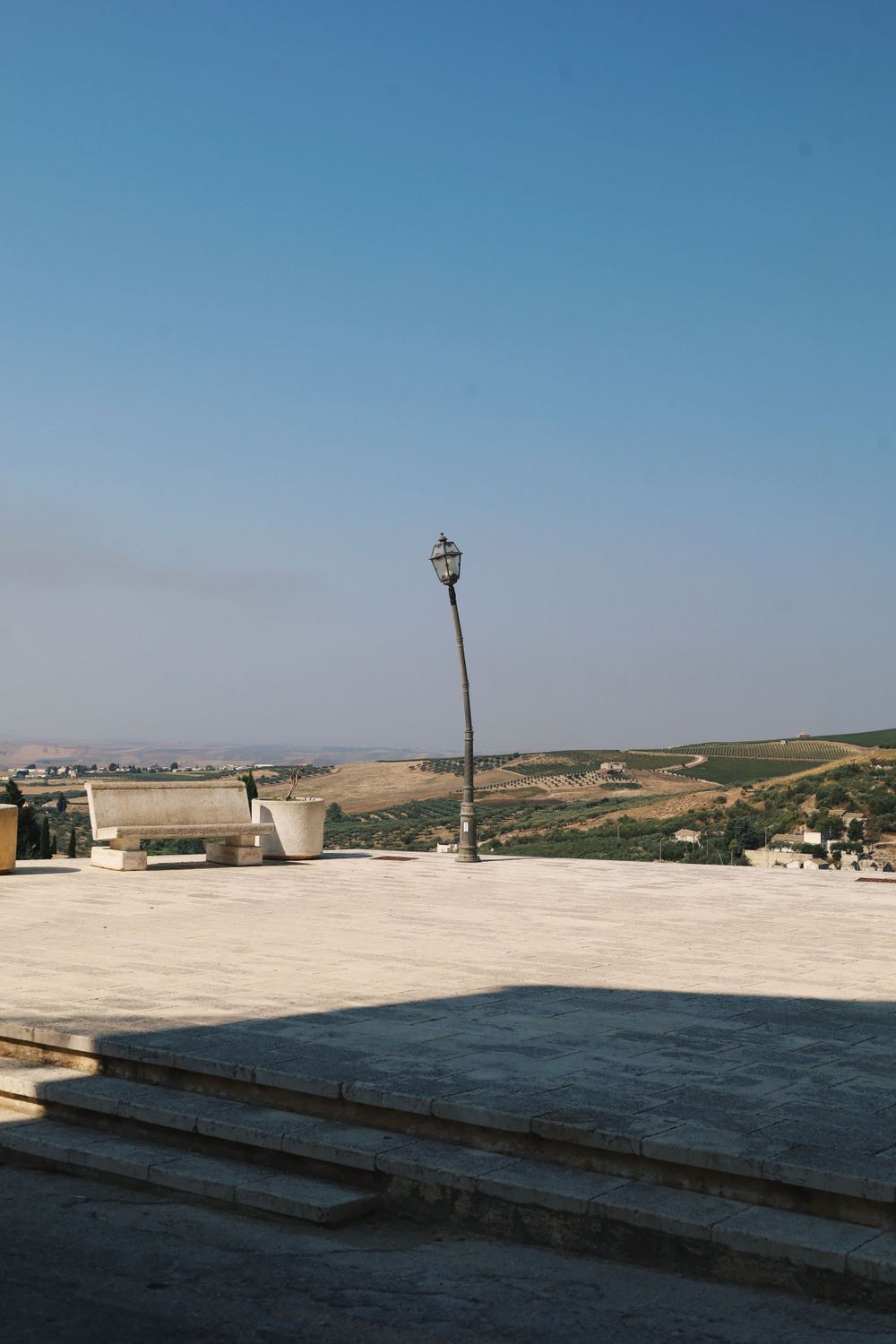 Concrete terrace overlooking a vast rural landscape under clear blue skies.