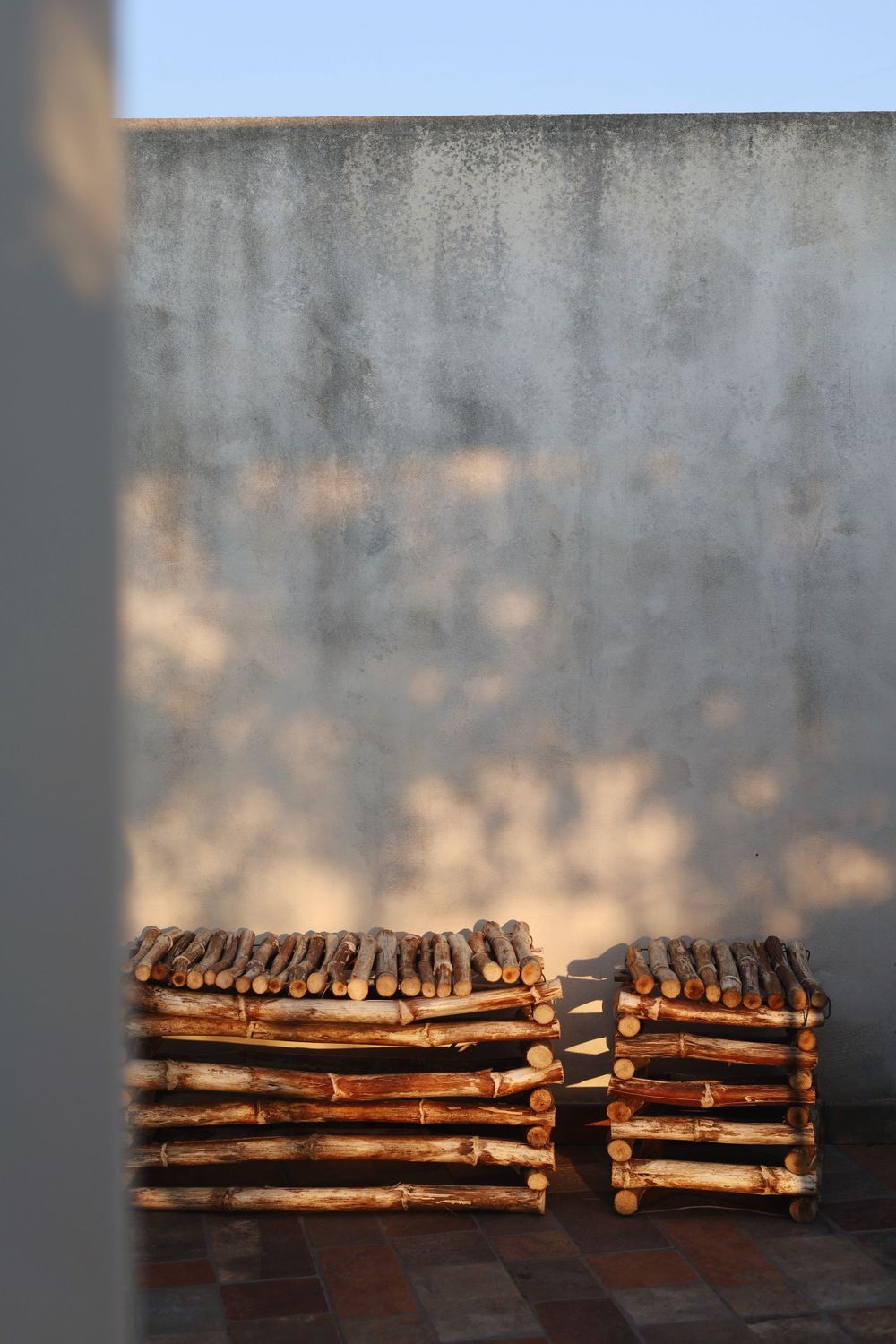 Stacked firewood logs arranged neatly against a gray concrete wall.