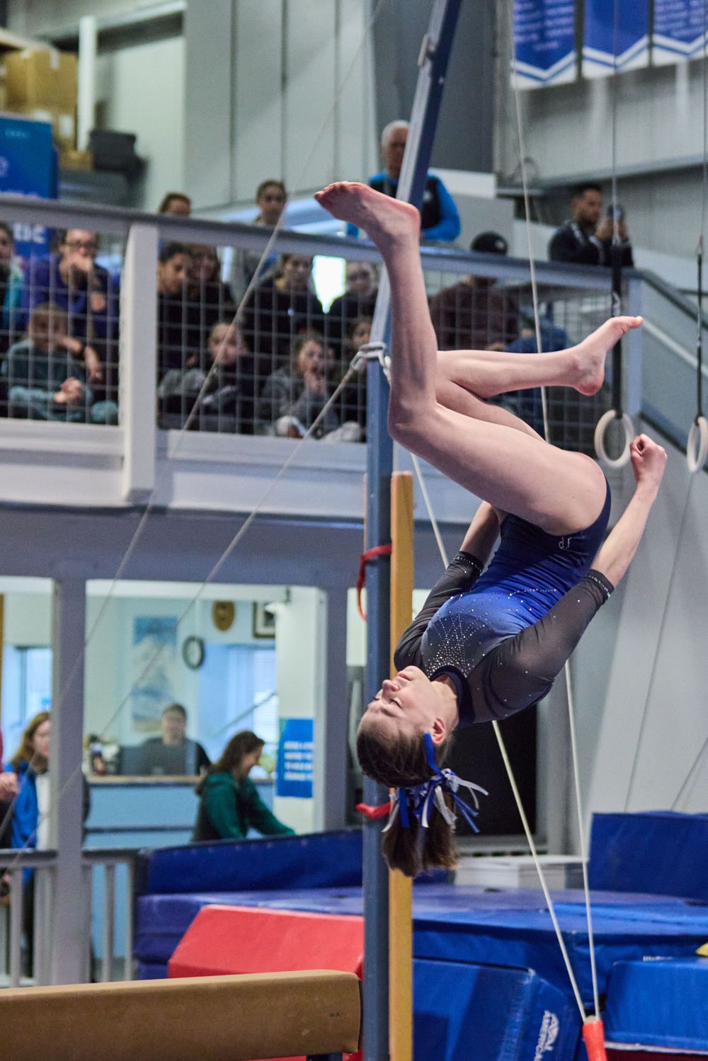Gymnast in blue leotard performs dismount from balance beam