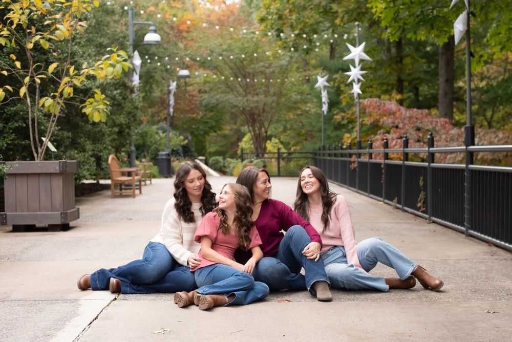 Three friends sitting together on a pathway with autumn decorations in the background.