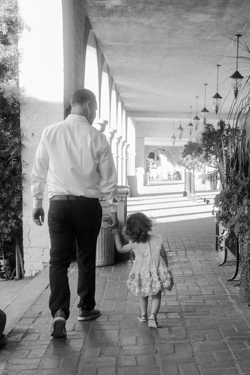 A black and white photo of a walk down an elegant covered colonnade.