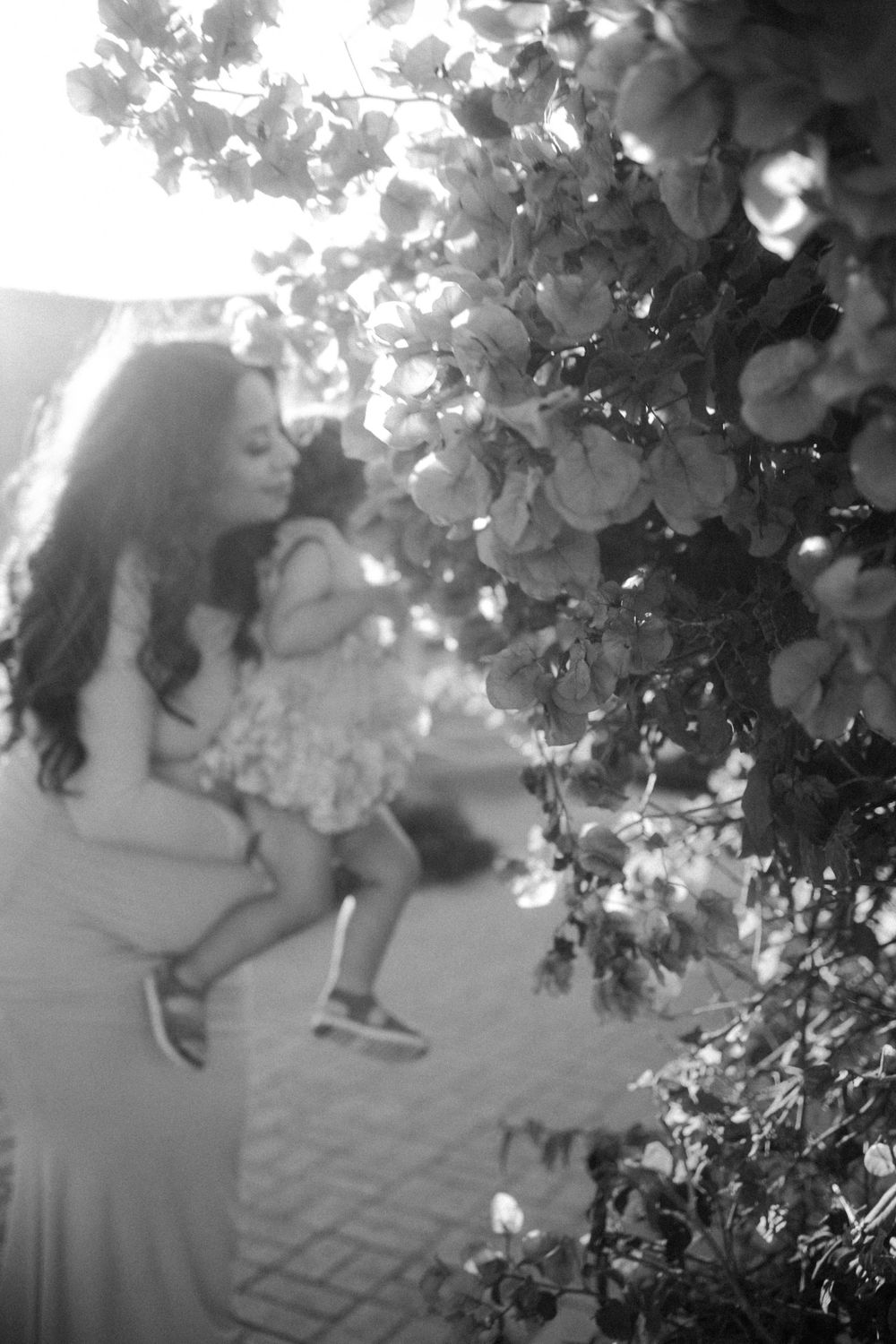 A black and white artistic maternity photo with flowering vines.
