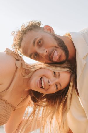 Close-up beach portrait of couple laughing in warm sunlight.