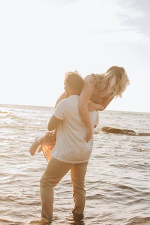 Playful couple dancing and embracing at the ocean's edge.