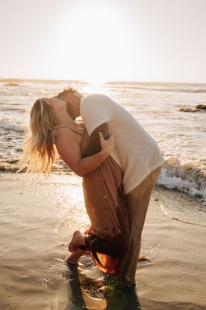 A romantic beach photoshoot with a couple sharing a passionate moment in the waves.