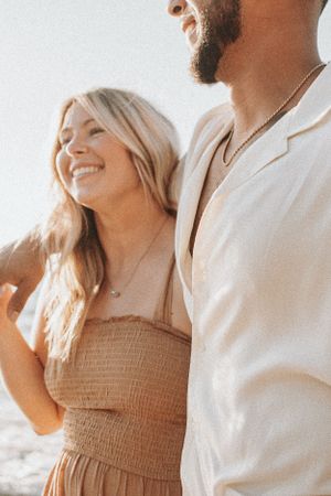 Romantic couple in beachwear embracing during a warmly lit photoshoot.