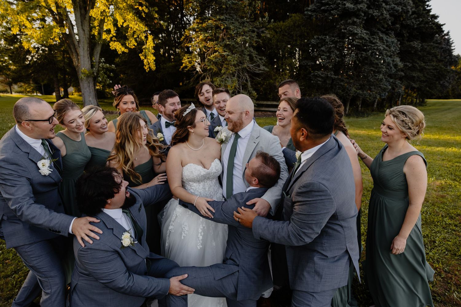 Wedding party/Bridal Party members embrace and celebrate outdoors during golden hour in Sheboygan, WI  with Essence Rose Photography.