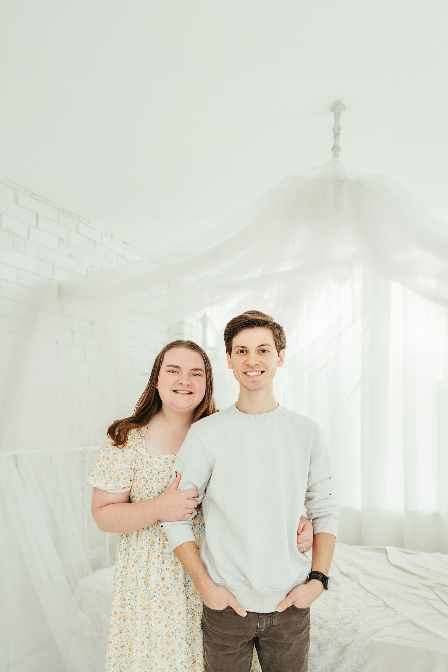 Smiling prom couple posing closely together outdoors in formal attire.
