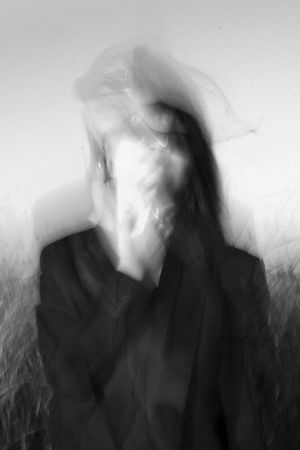 Blurred black and white artistic portrait showing abstract motion and distortion with ethereal ghostly effect.