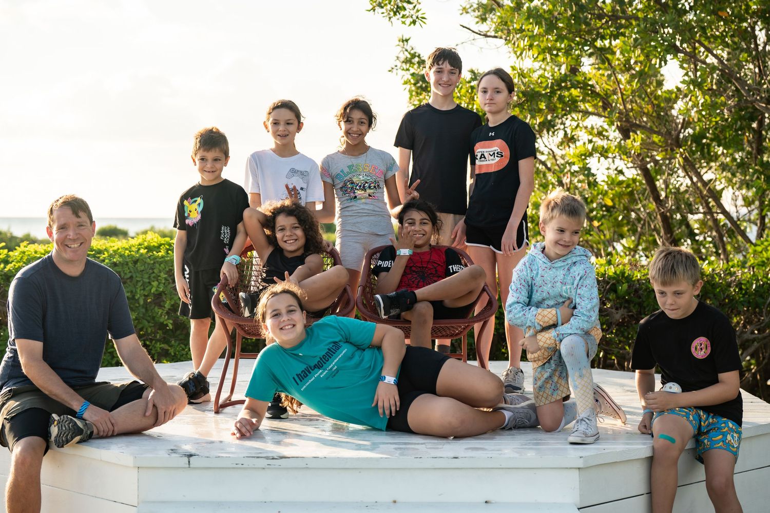 Group of people sitting outdoors in casual attire enjoying a sunny day together.