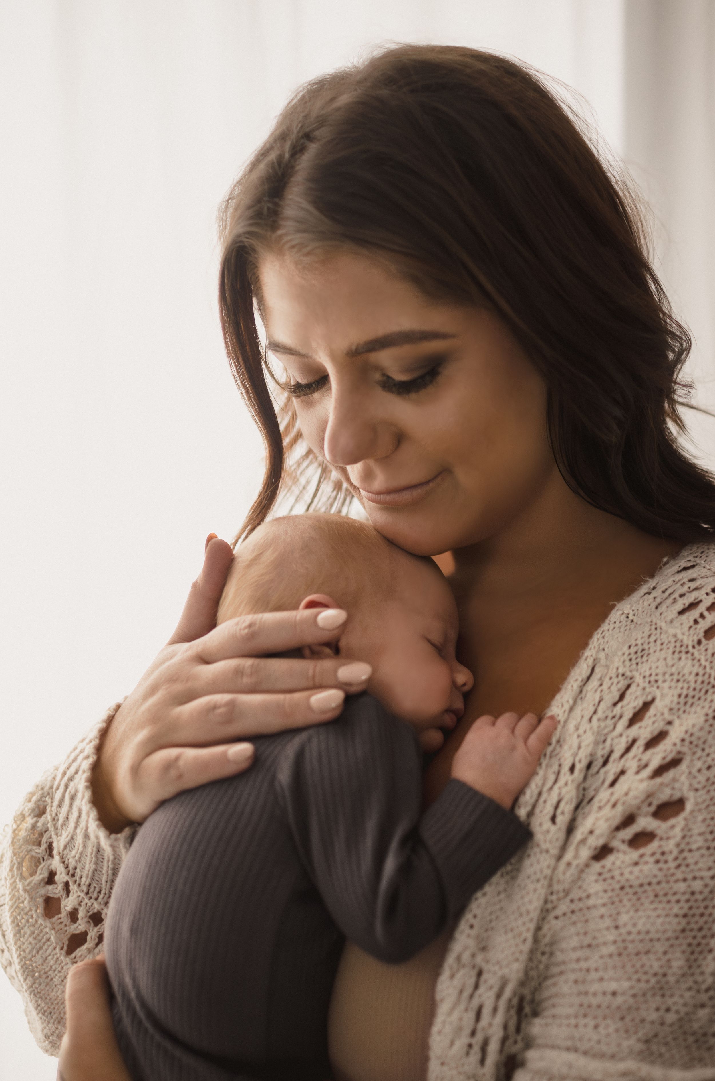 A tender moment captured as a mother holds her sleeping newborn baby against her chest.