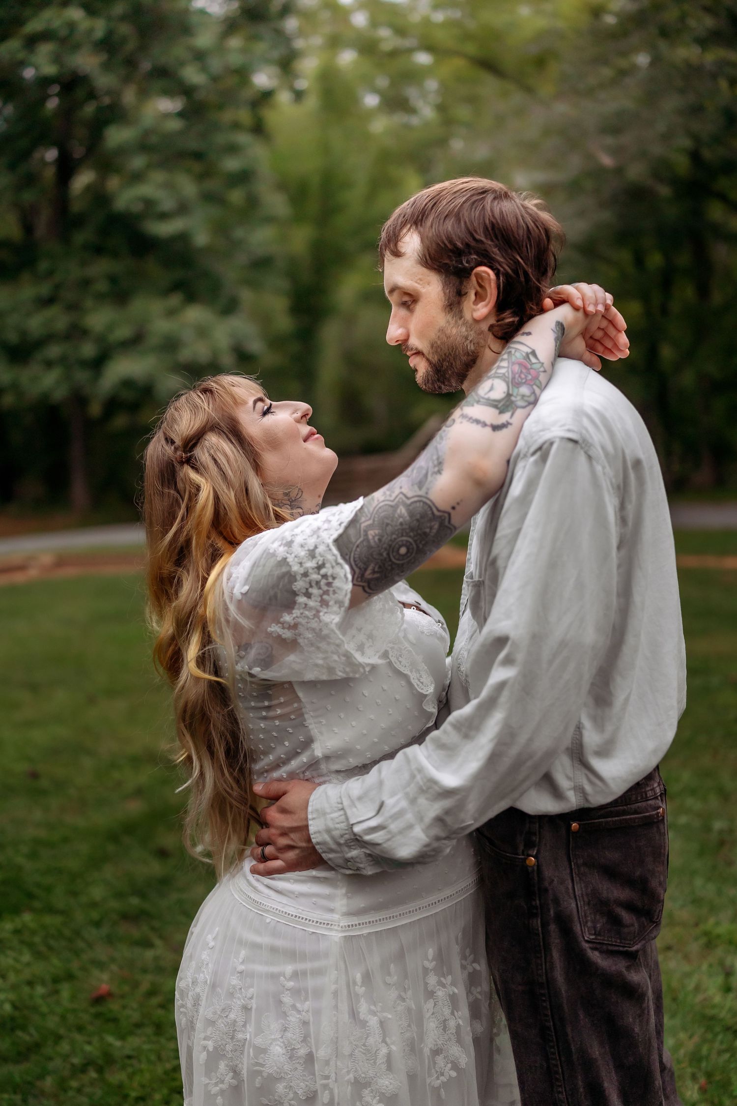 A couple in vintage-inspired clothing share a romantic dance outdoors in a park setting.