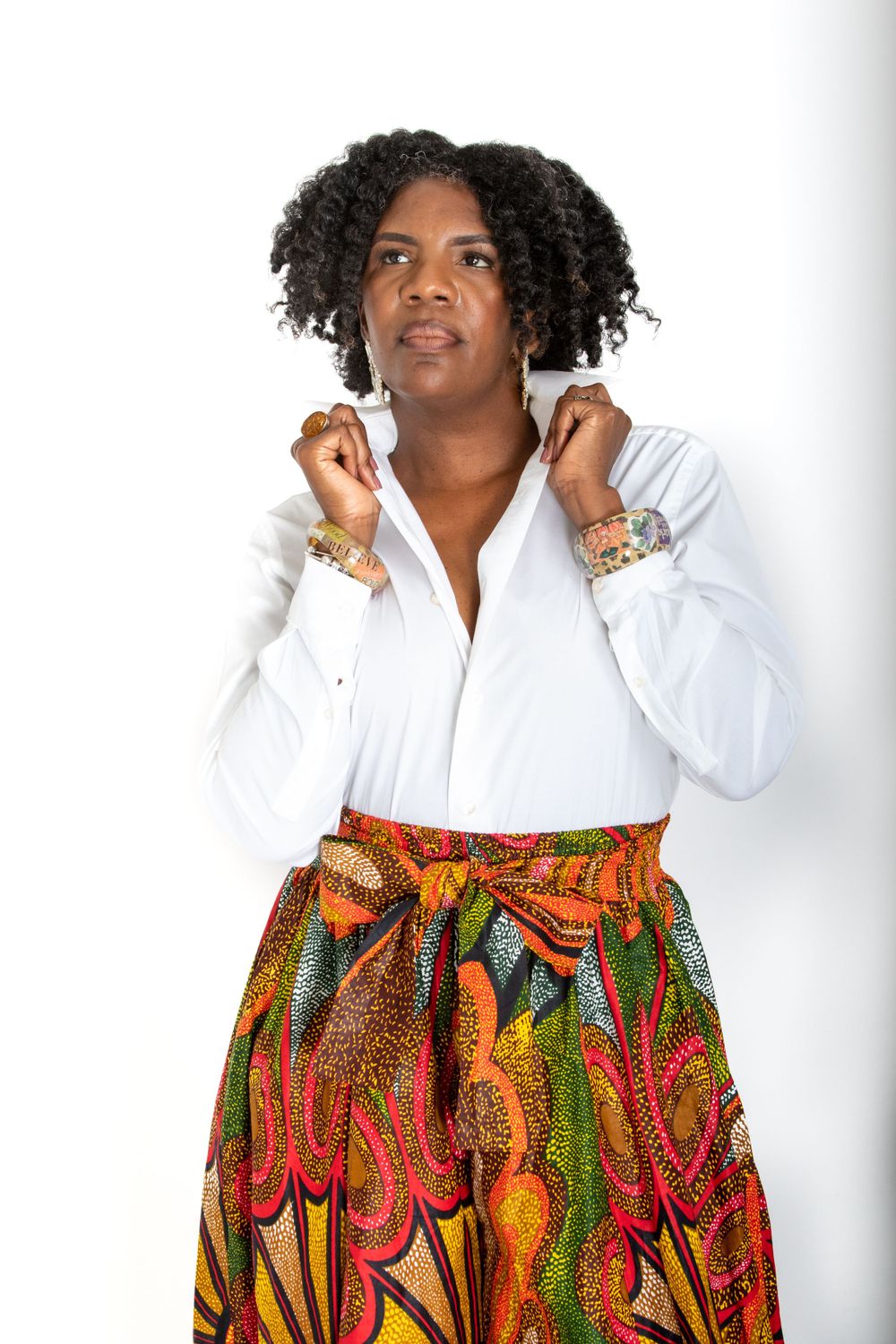 Person wearing white shirt and colorful patterned maxi skirt poses against white background.