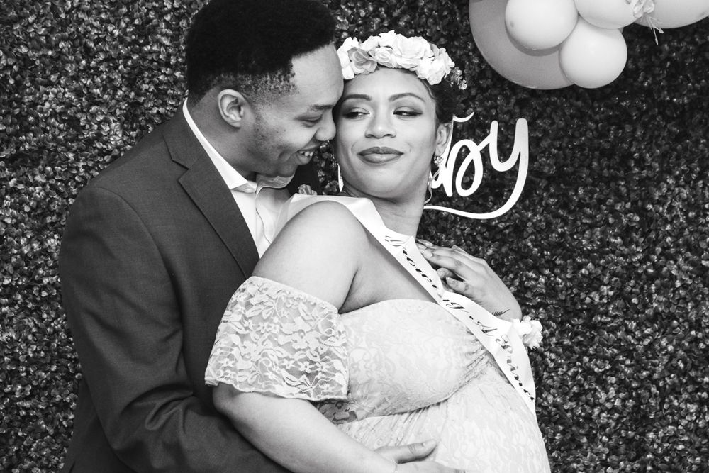 A black and white photo of a couple at a baby shower celebration with floral crown.