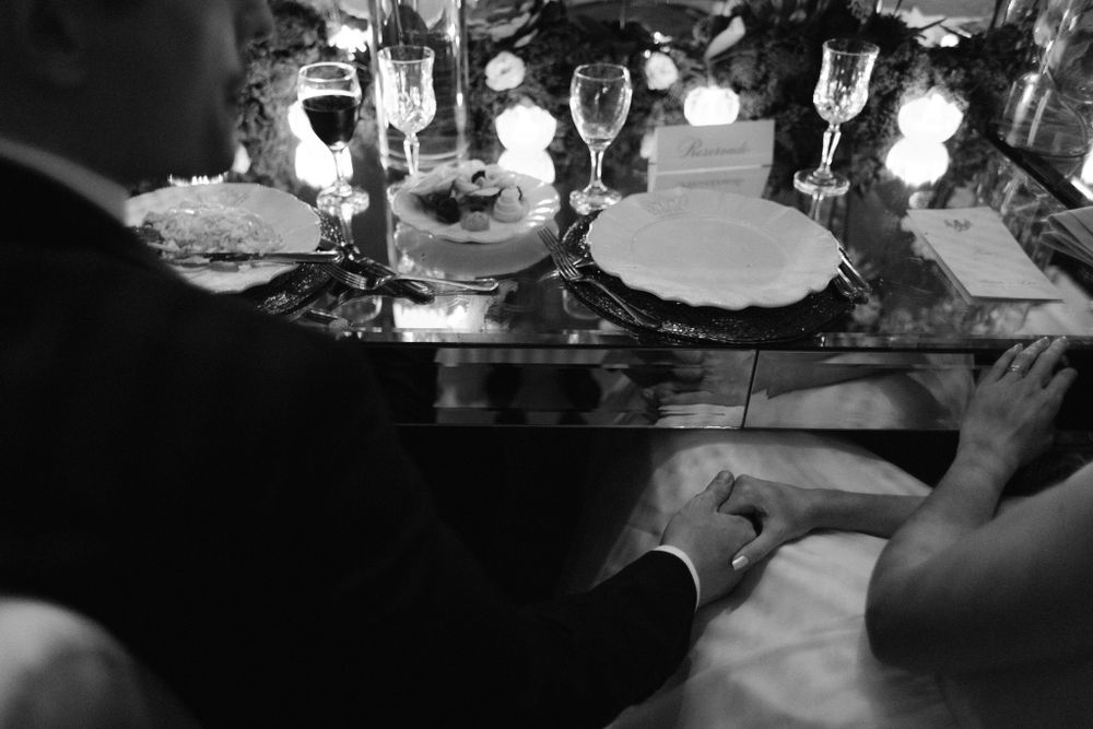 Elegant table settings with crystal glasses and fine china reflecting in candlelight at a formal dinner.