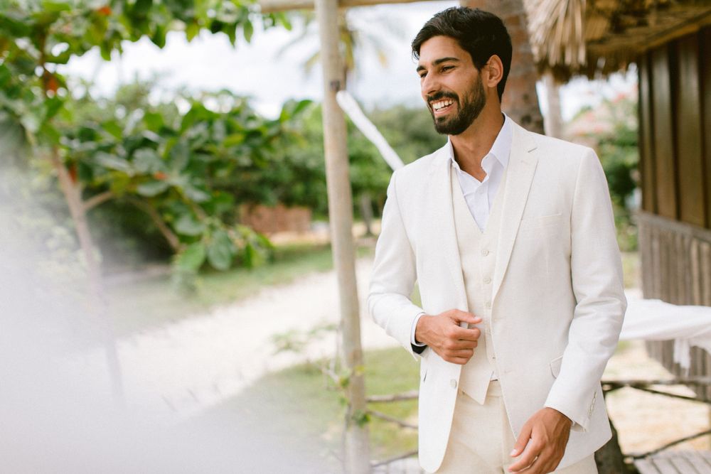 A tropical setting with a person in a crisp white suit against lush greenery.