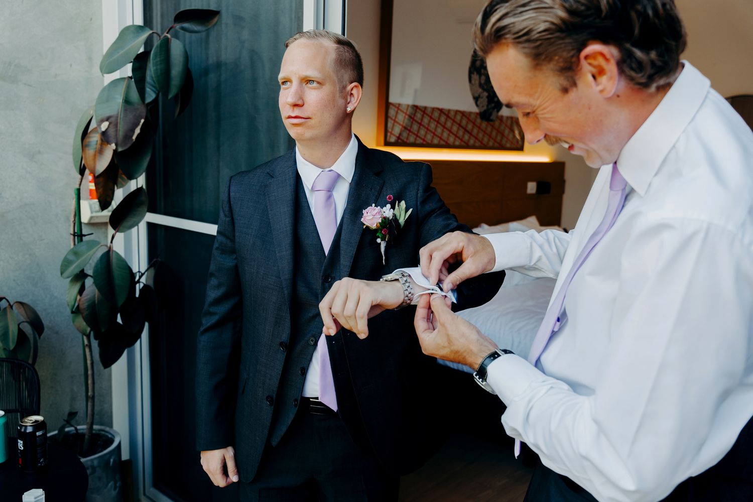 Wedding preparation scene with formal attire adjustments being made.