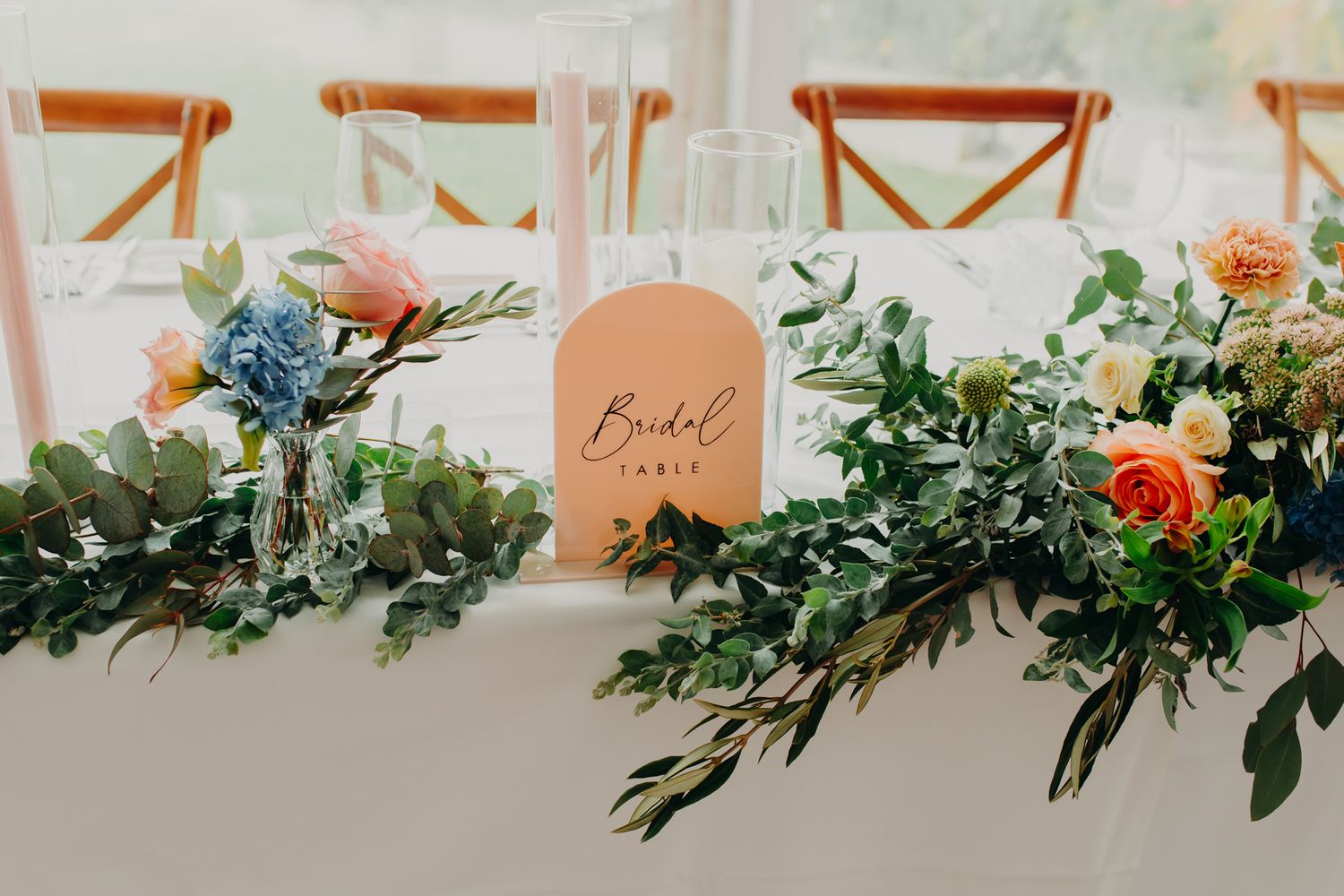 Wedding table decor with coral roses and eucalyptus garland centerpiece.