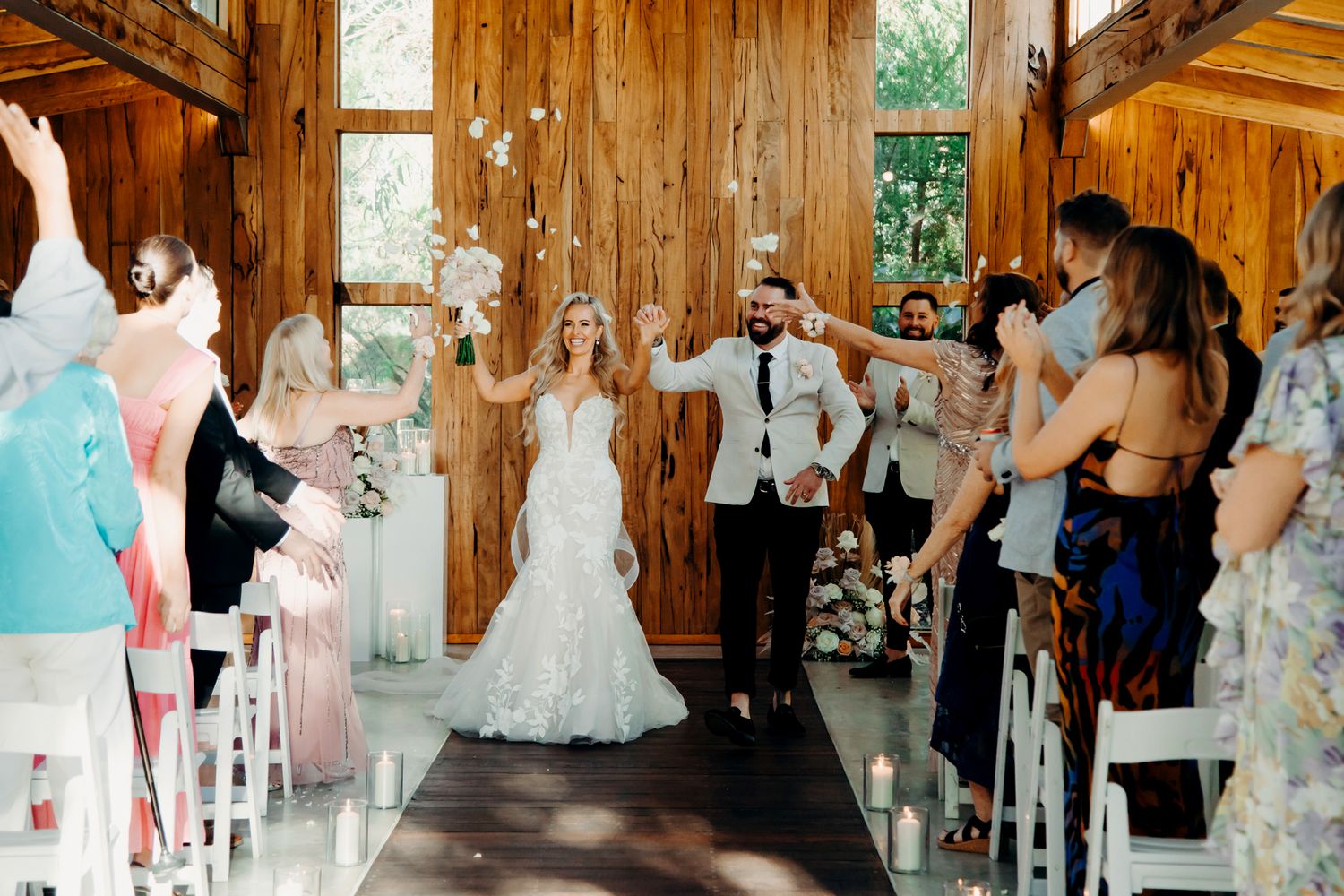 Wedding ceremony taking place in a rustic wooden barn venue with natural light streaming through windows.