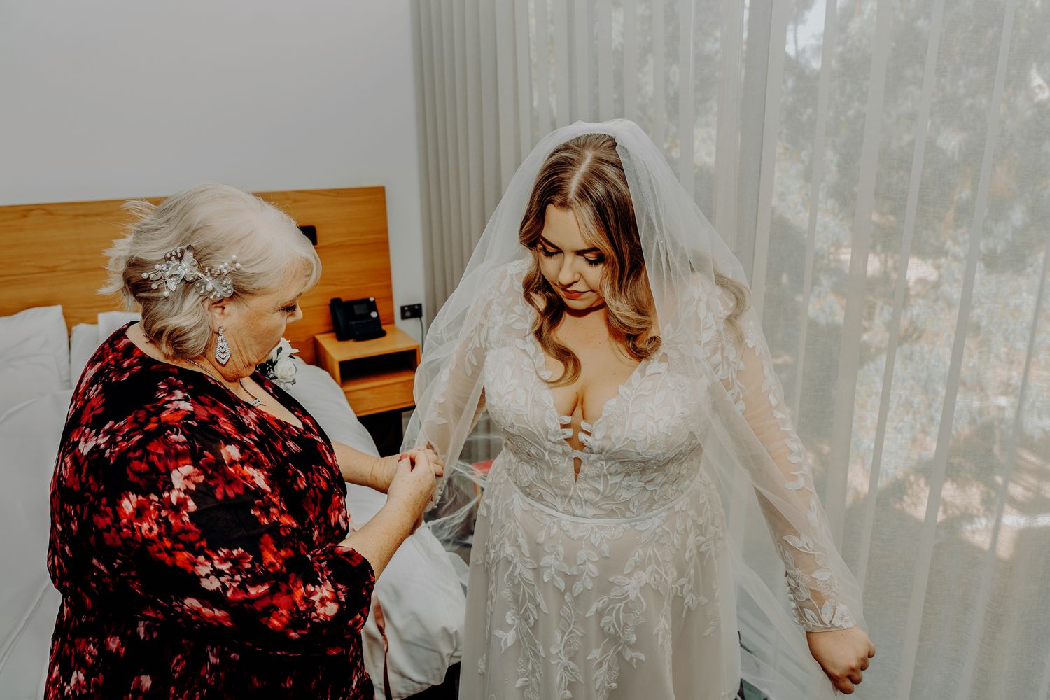 A wedding dress preparation moment with elegant lace details and flowing veil.