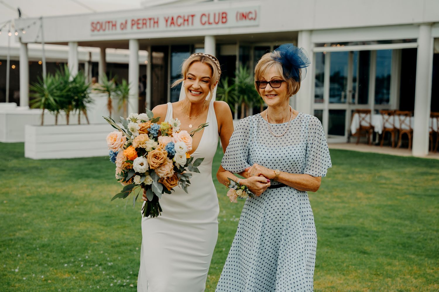 A wedding celebration outside the South of Perth Yacht Club with floral bouquets and blue decor.