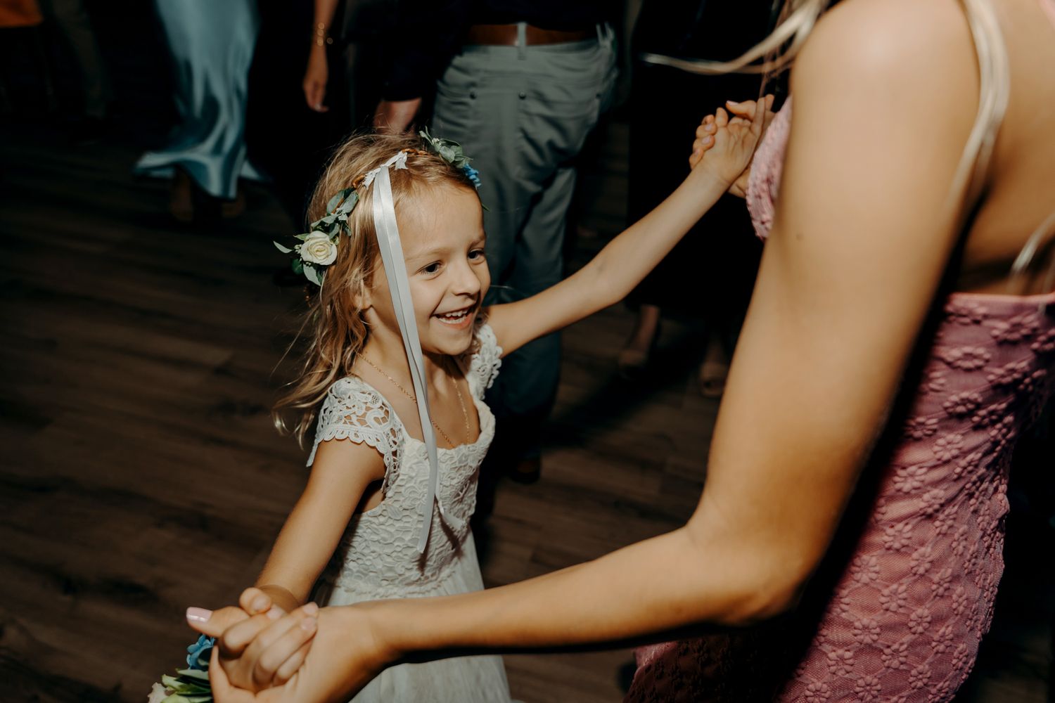 A young flower girl dances joyfully at a wedding reception.