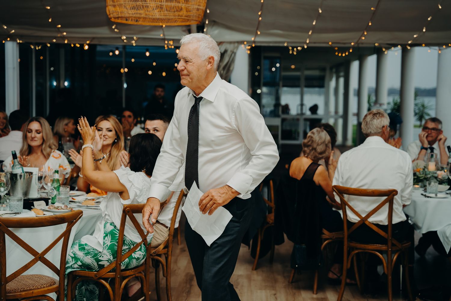Wedding reception guests dancing and celebrating under string lights.