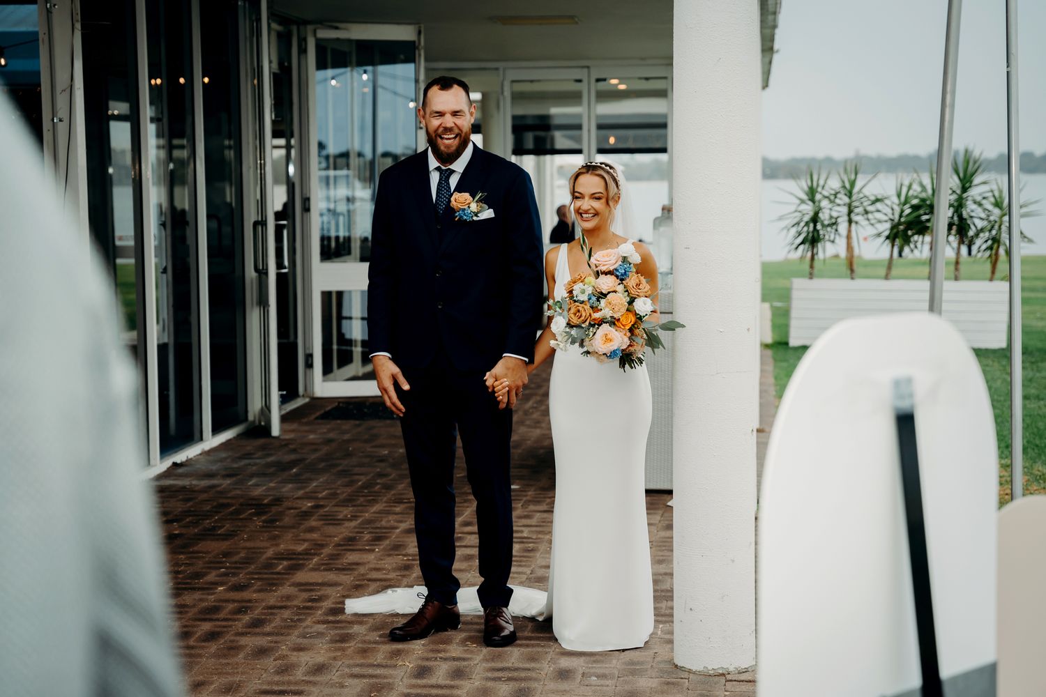 Modern coastal wedding photo of couple standing by architectural elements.