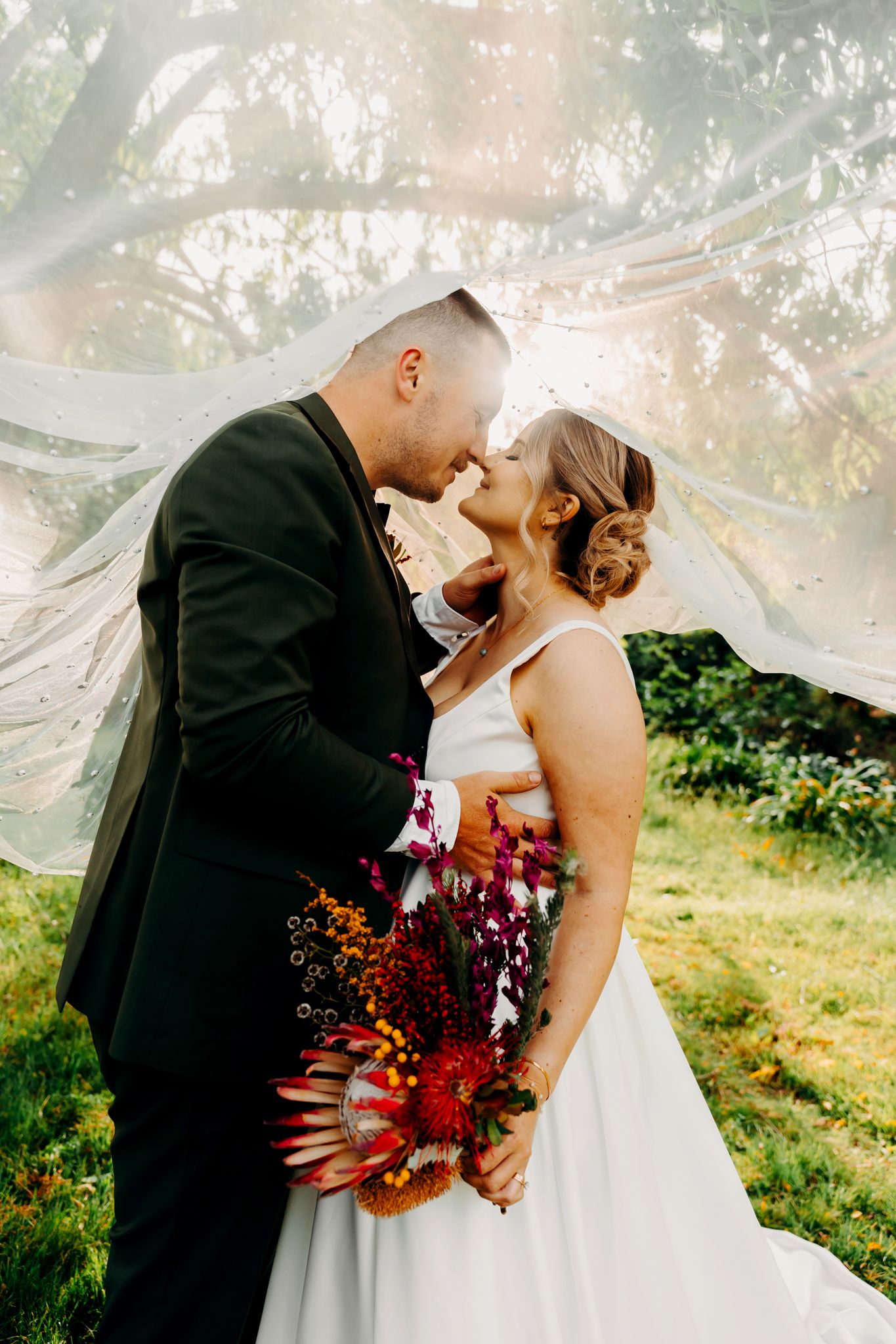 Romantic wedding portrait with flowing veil and vibrant fall bouquet.