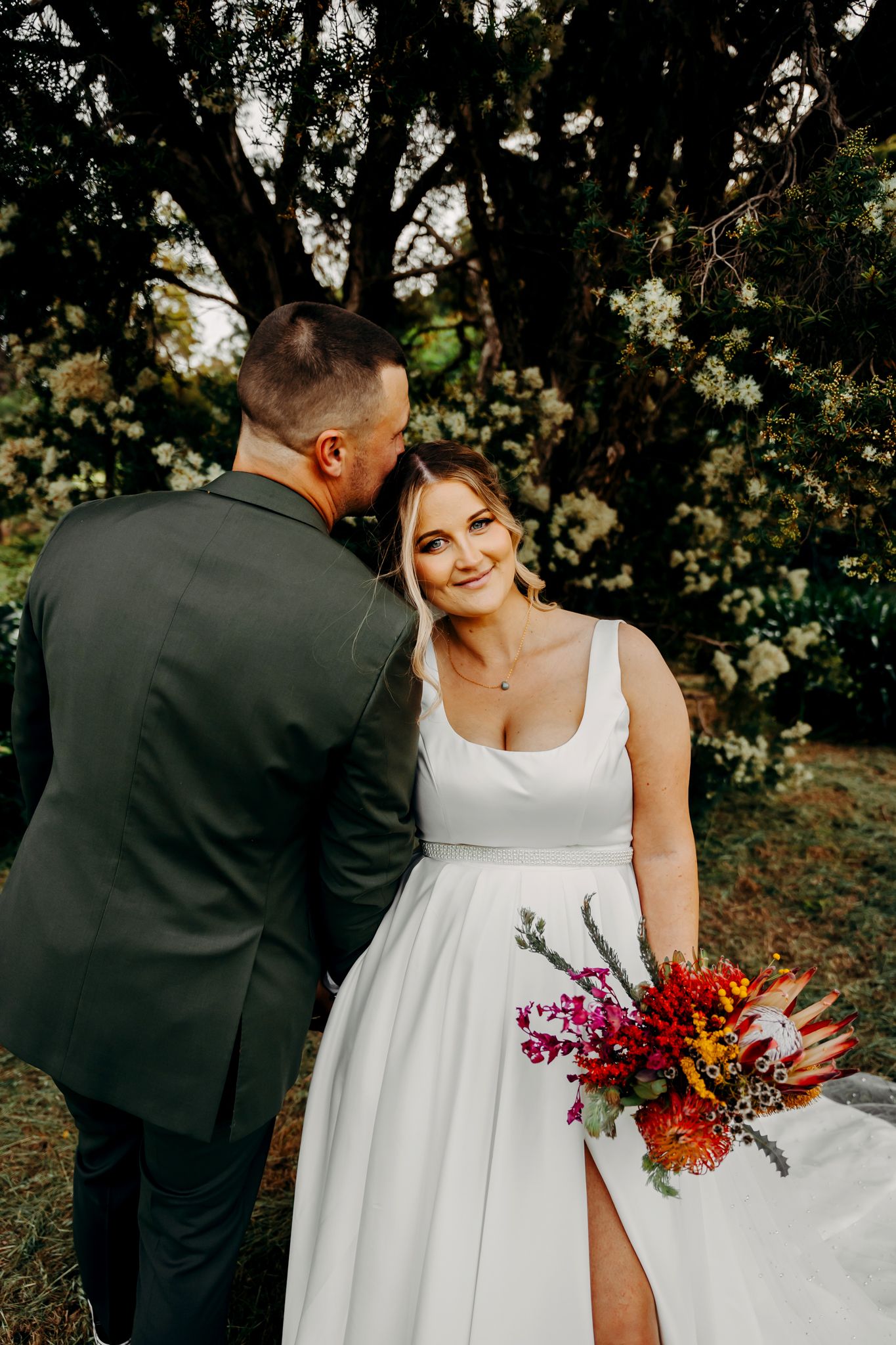 Intimate wedding portrait showcasing elegant white dress and colorful autumn bouquet.